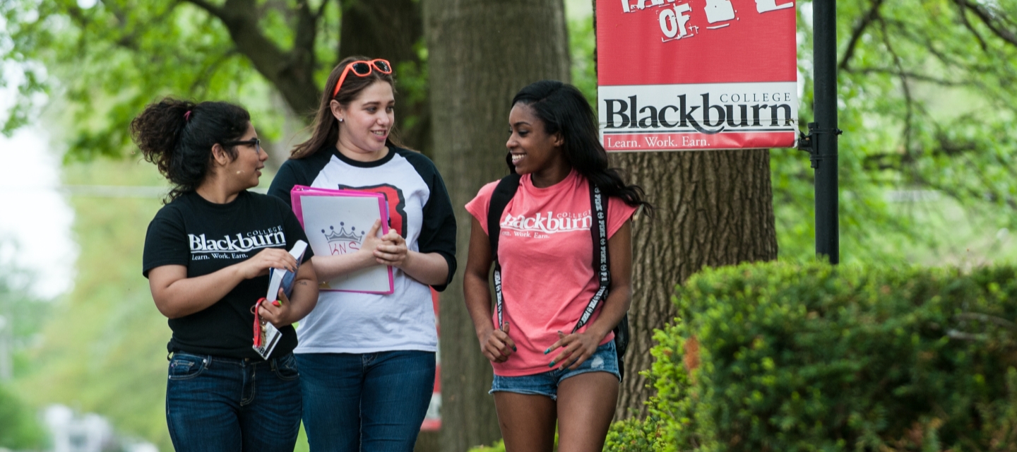 Three Blackburn students walking across campus while holding a conversation.