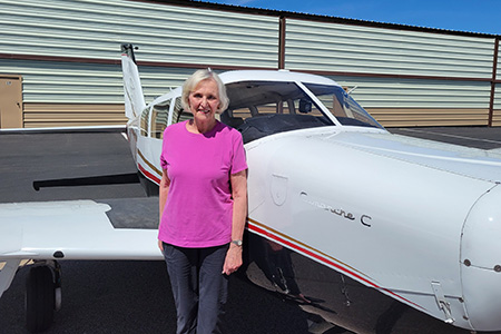 Dr. Lois Begitske DeFleur posing right next to an airplane.