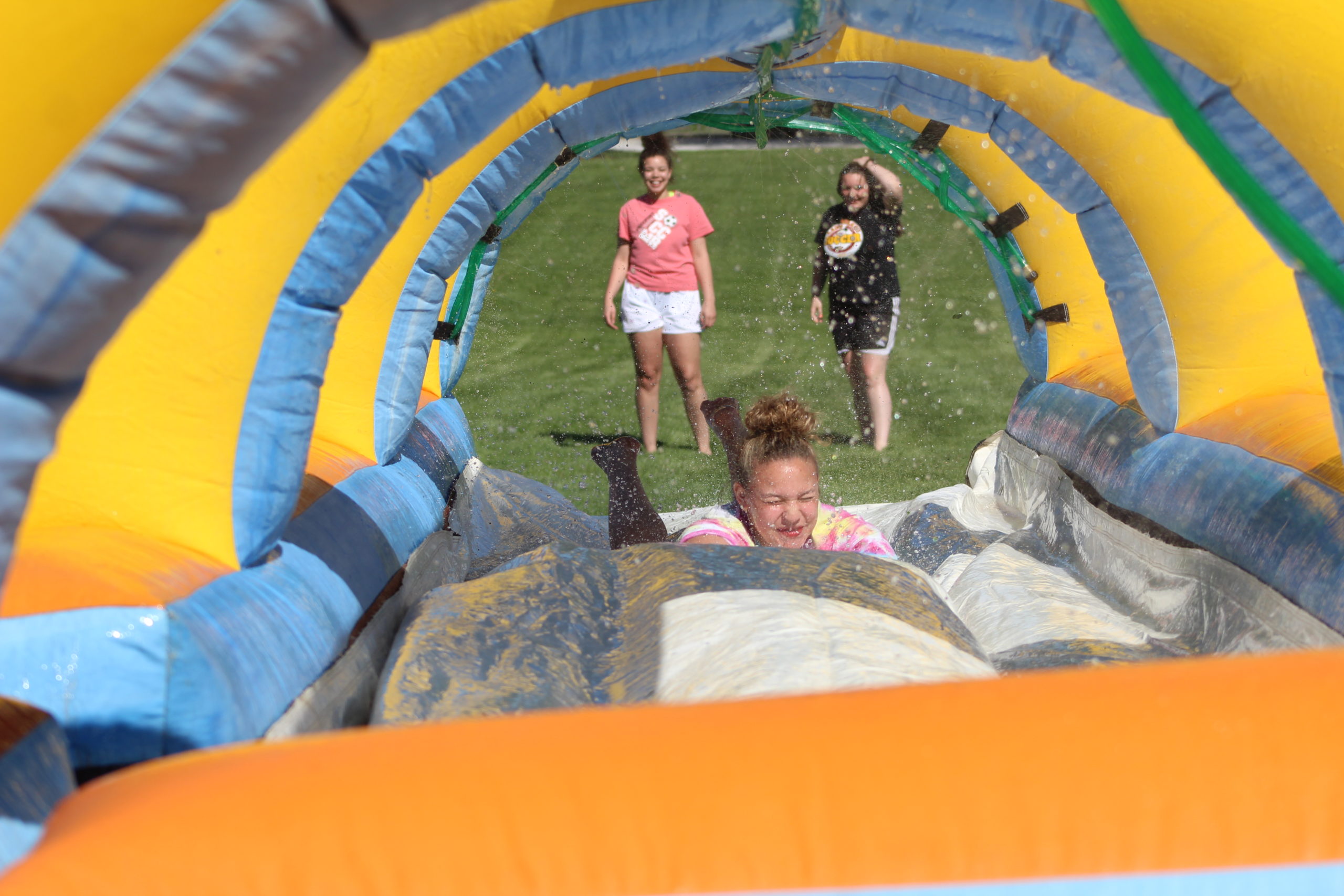 Blackburn student going through a water slide as two other students stare at her in the background.