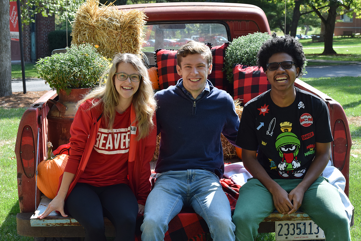 Three Blackburn students sitting on the trunk of a vintage truck during the 2021 Homecoming festivities.