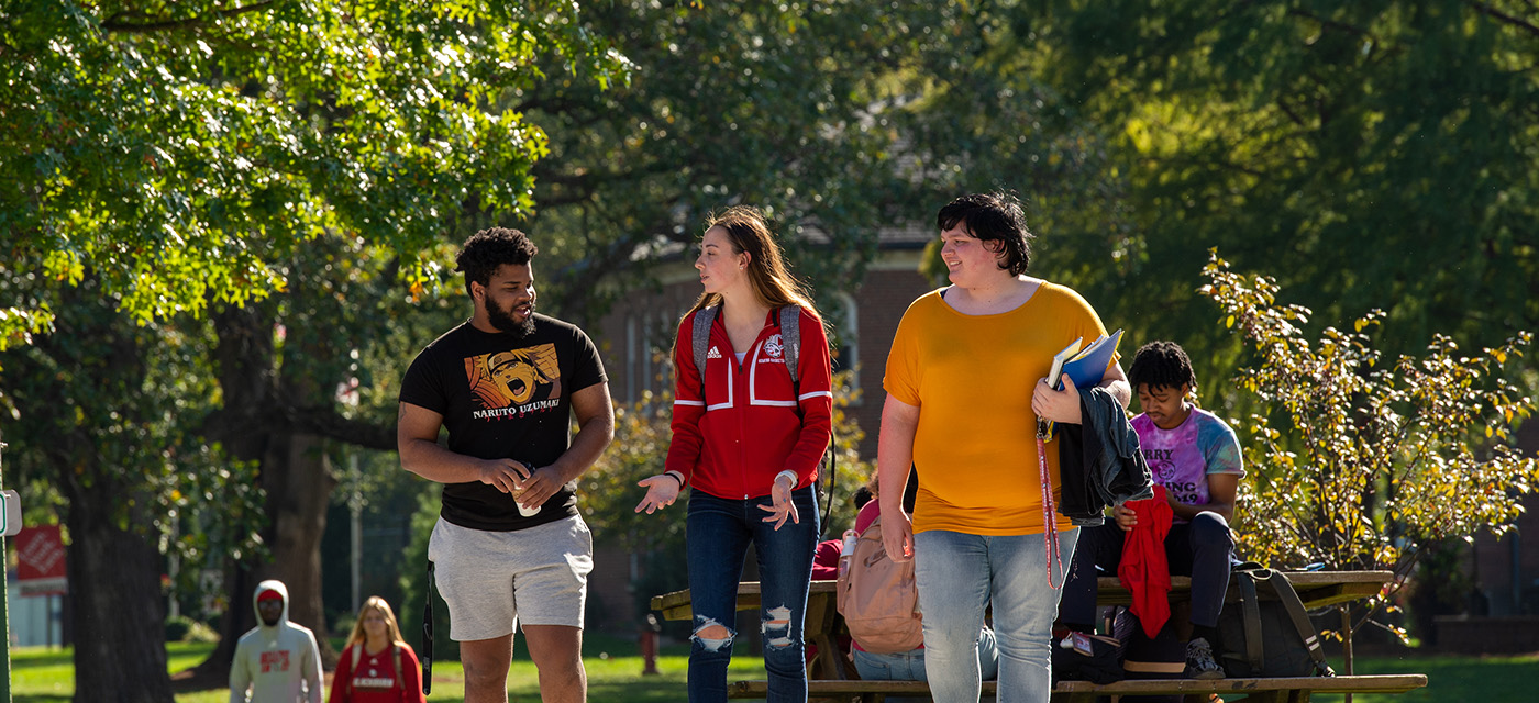 Three Blackburn students walking across the multitude of students on campus.