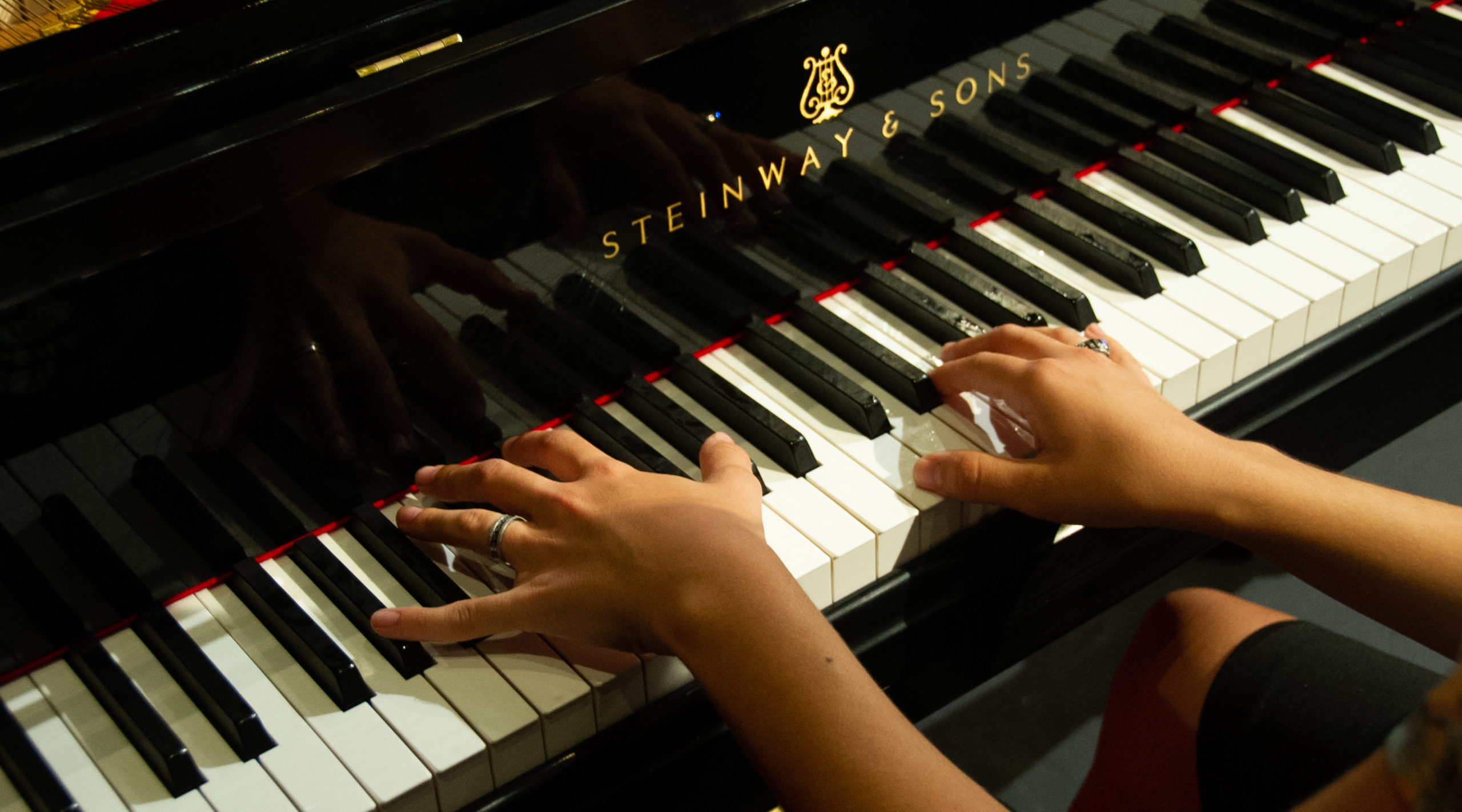 Close-up shot of hands playing a Steinway & Sons piano.