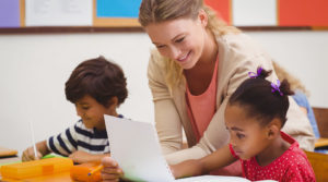 Early Childhood Teacher helping students in classroom.