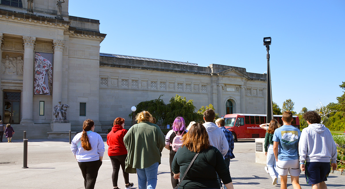 Several Blackburn College Art students walk outside toward the exterior of the St. Louis Art Museum