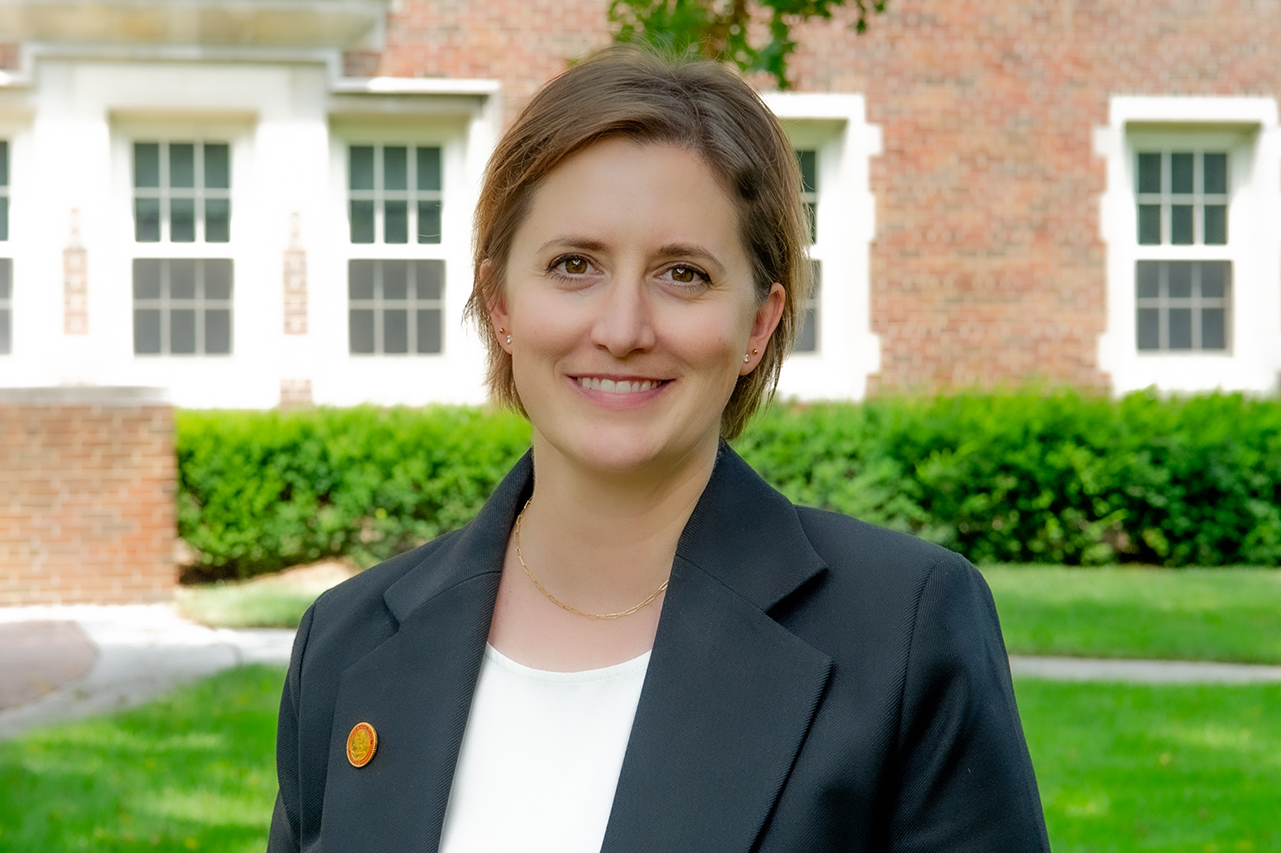 Provost Dr. Laura Wiedlocher headshot, smiling woman in front of brick building