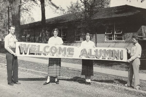 old photo with Blackburn students in the 1950s holding a hand-painted "Welcome Alumni" banner