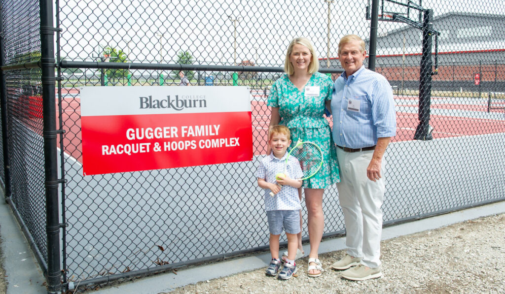 Joe Gugger '72, his daughter and grandson pose in front of sign for Gugger Family Racquet and Hoops Complex at dedication ceremony