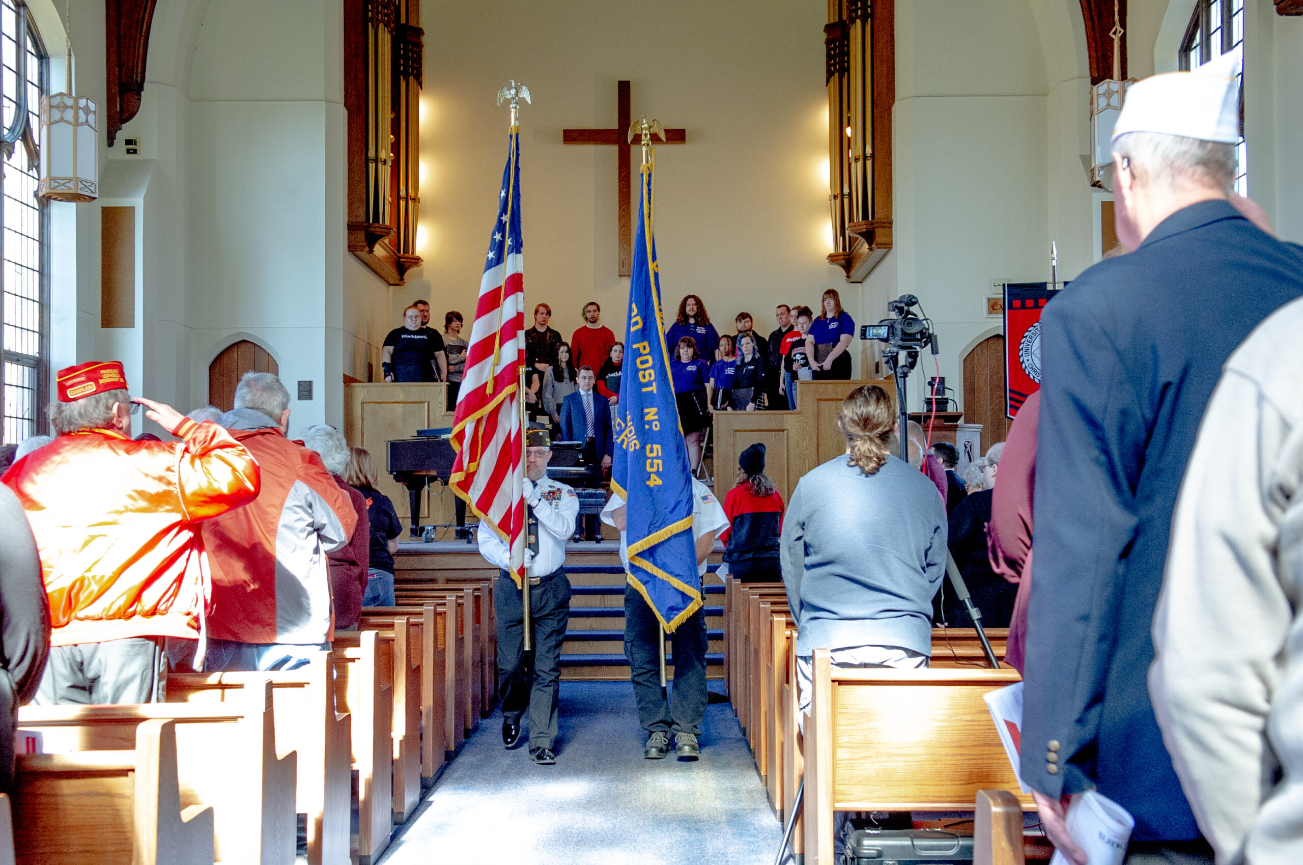 People standing and saluting the Color Guard being presented during the Veterans Day Convocation in Clegg Chapel.