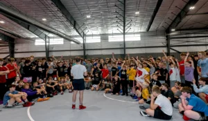 Wrestling Clinic - Blackburn Athletic Center - children gathered around speaker raising their hands