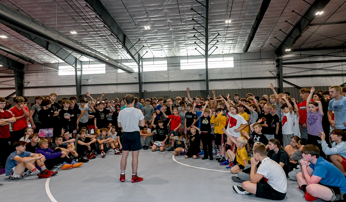Wrestling Clinic - Blackburn Athletic Center - children gathered around speaker raising their hands
