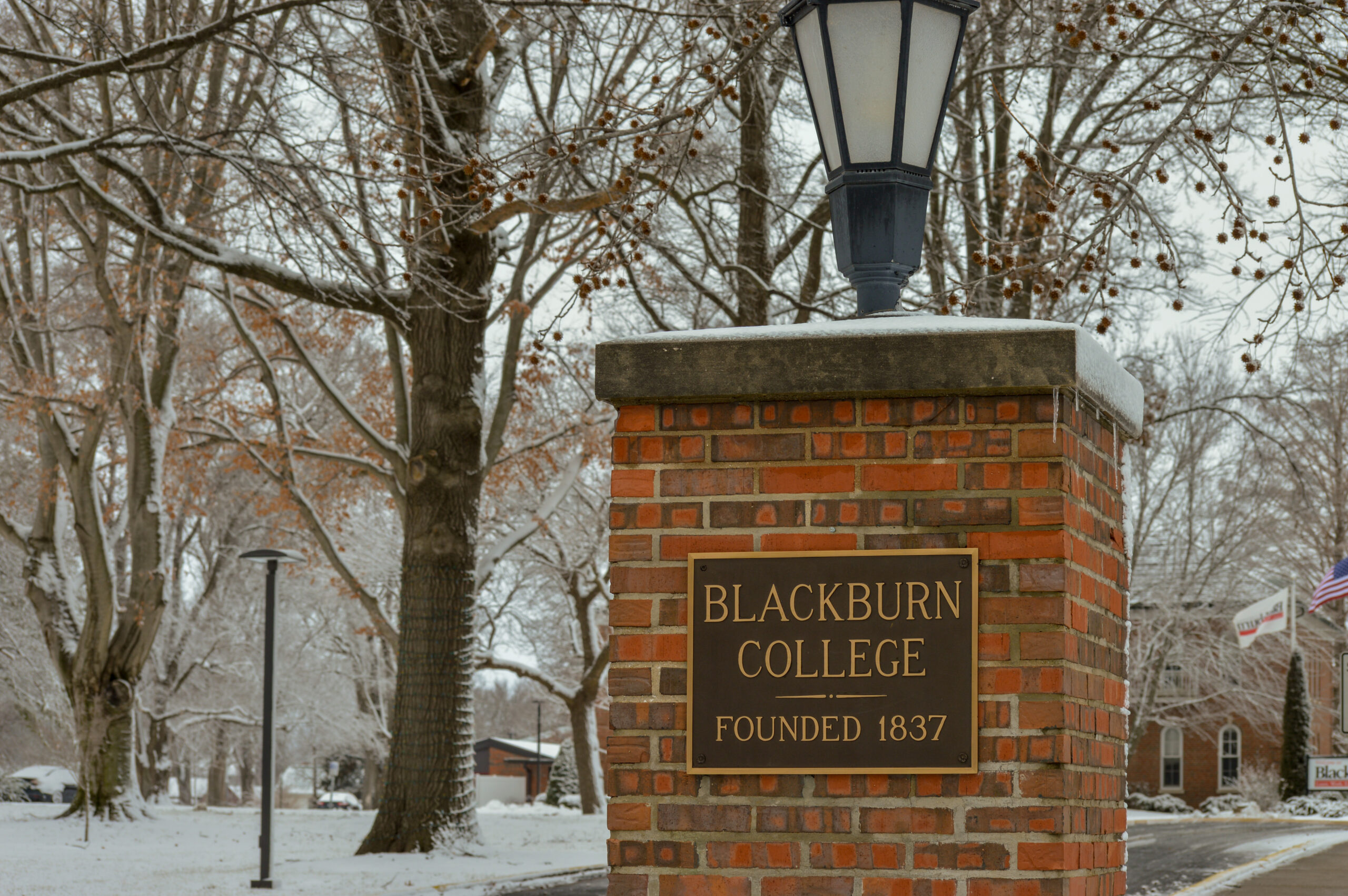 Brick column at front entrance to college, with Blackburn College sign, surrounded by snowy trees