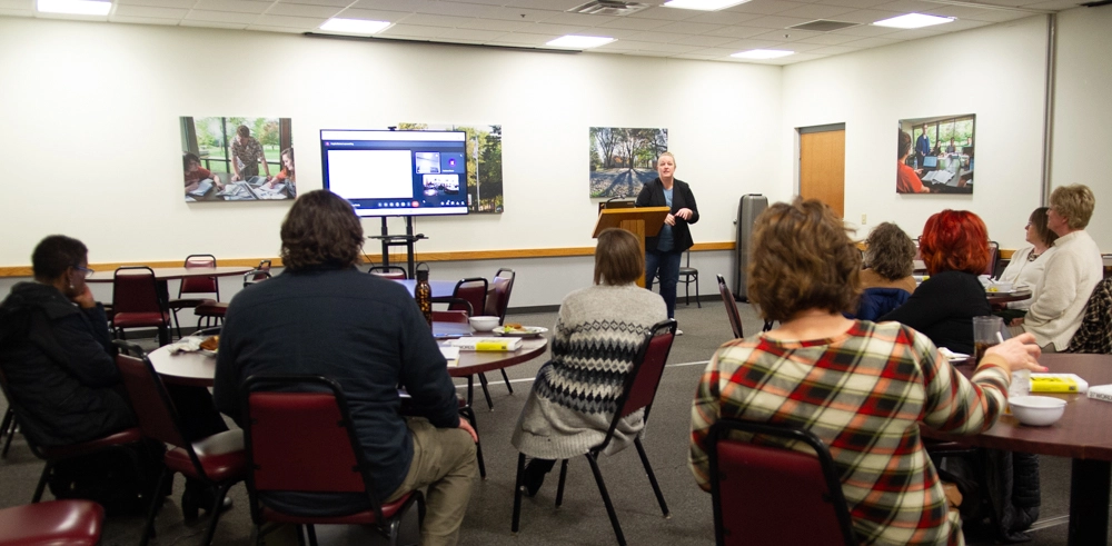 Diversity Learning Circle in the Auxiliary Dining Rooms - people seated at tables as presenter stands at podium with power point presentation