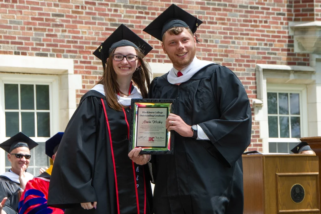 Student Marshal and Outstanding Graduate Alexis Mosby '25 is handed award by Blackburn Cross Country and Track coach and Alumni Association President Noah Daum '18
