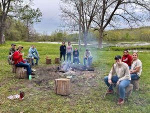 A group of students sit around camp fire during field biology opportunity