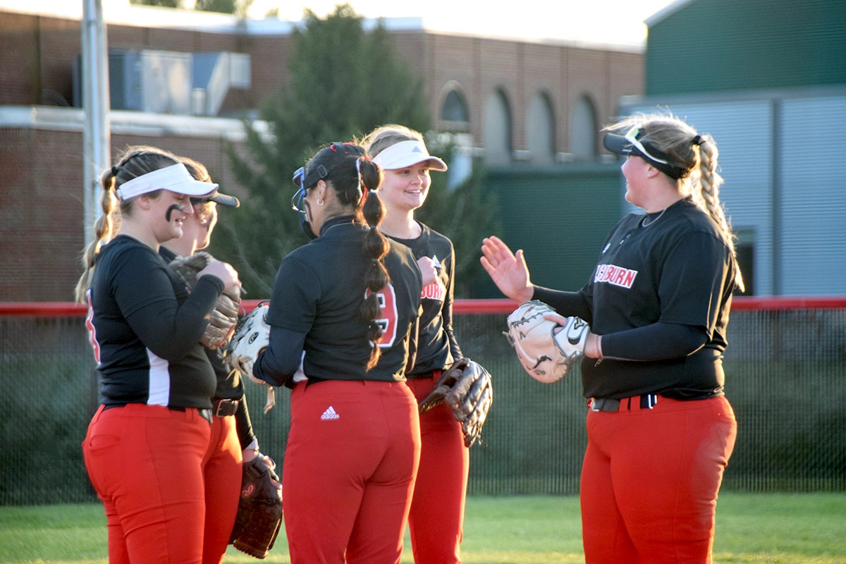 Softball team gathers at the pitcher's mound during game