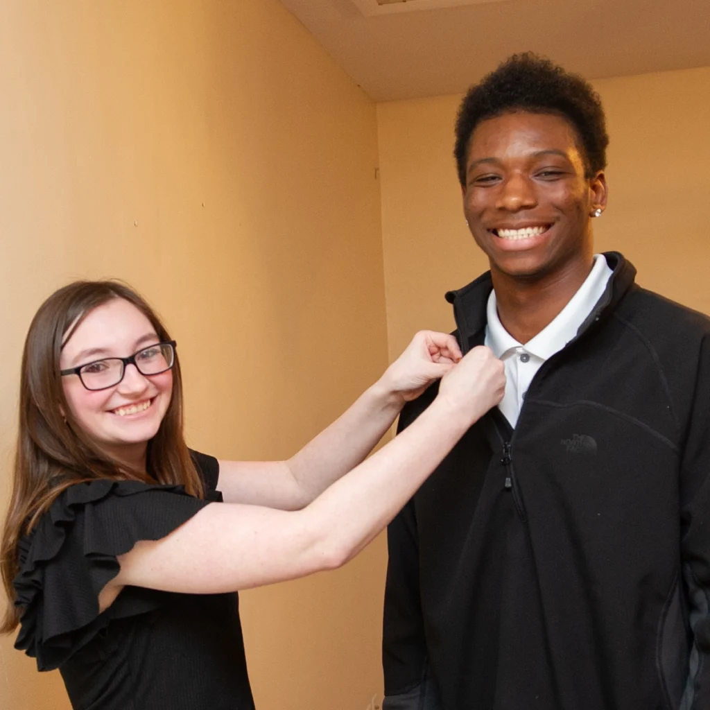 Student attaches pin to Darius Duff's collar during Work Program Manager Pinning Ceremony.