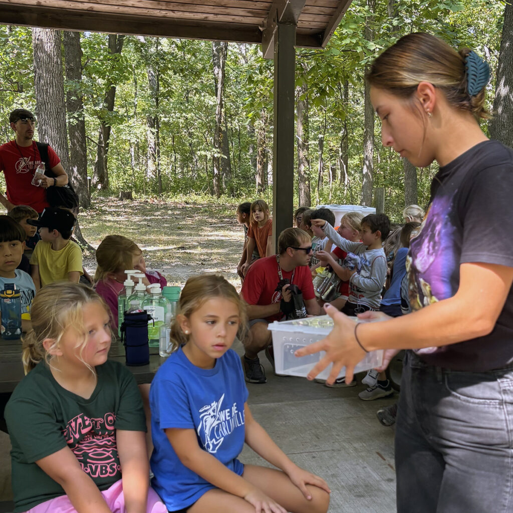 Blackburn student holds a container with a python for second graders to observe