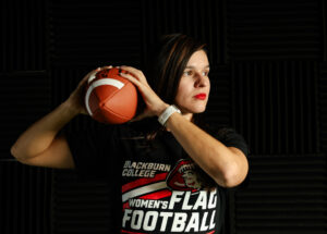 Coach Stephanie Aragon holds football and prepares to throw a pass