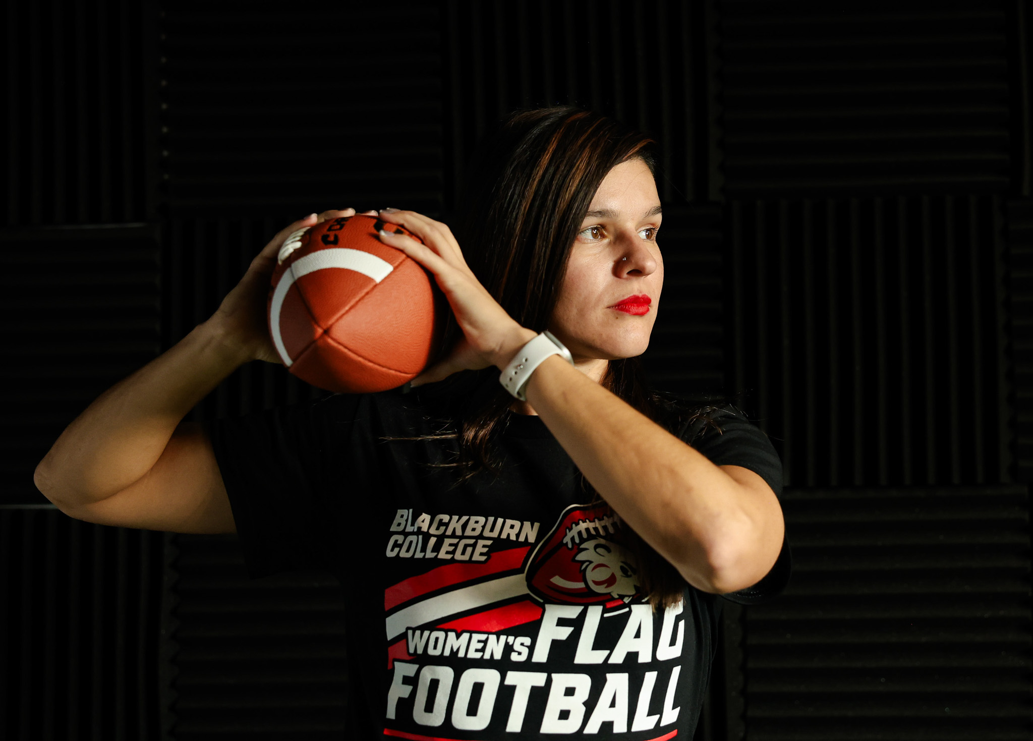 Coach Stephanie Aragon holds football and prepares to throw a pass