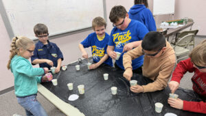 Regional Cub Scouts gather around a table with protective eyewear
